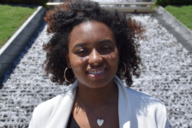 一位骄傲的年轻有色女商人，身穿白色运动上衣，在国家公园户外活动;背景是瀑布。图片下载