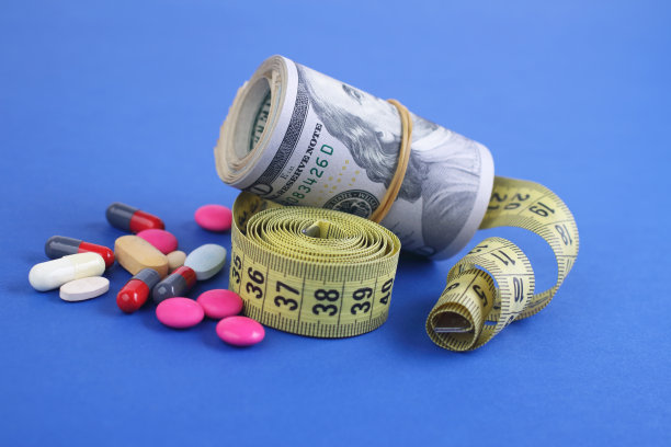 一卷带卷尺的钱和药片，减肥成本的概念。图片下载