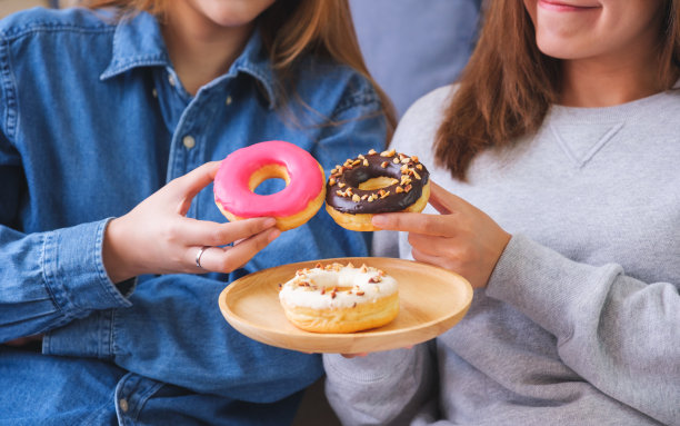 闺蜜两人的特写照片，她们一起拿着甜甜圈吃图片下载