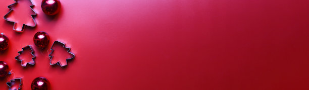 横幅平平地为圣诞树准备了圣诞玩具。姜饼的模具。红色背景的圣诞装饰品图片下载