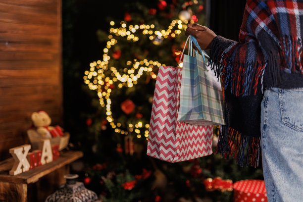 年轻女子走到圣诞树前把礼物袋放在下面图片下载