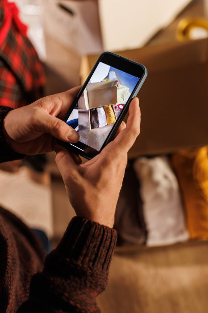 一个年轻人正在为一个装满捐赠衣物的盒子拍照图片下载