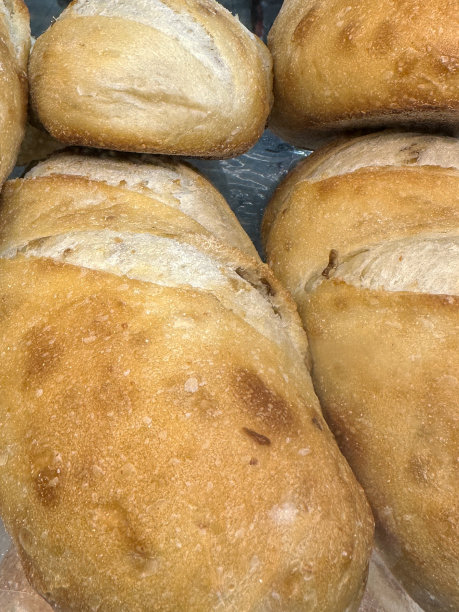 特写图片:一排排的手工面包堆在玻璃面包店的架子上，白色的酸面包，聚焦于前景，高架视图图片下载