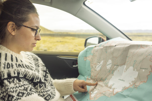 坐在驾驶座上看城市地图的女人。冰岛图片下载