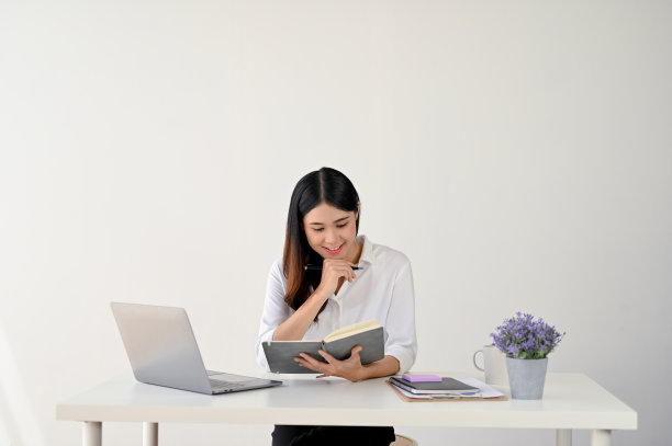 一位迷人的年轻亚洲女商人正在阅读或检查她笔记本上的一些细节图片下载