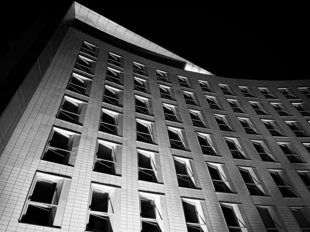 白色的办公楼，晚上有一排排开着的窗户图片下载