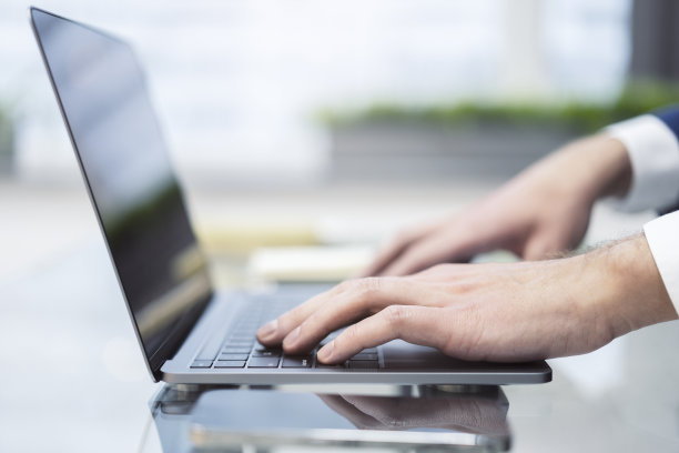 这张照片以模糊的办公室场景为背景，特写了一群忙于在一台尖端笔记本电脑上打字的男性图片下载