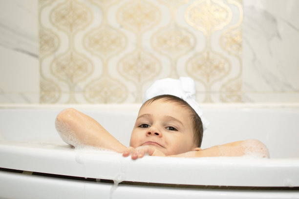 头发上有肥皂泡沫的可爱孩子在洗澡。微笑的儿童肖像特写，照顾儿童的健康和卫生。婴儿洗发水。快乐童年，卫生护肤程序。图片下载