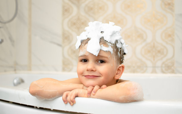 头发上有肥皂泡沫的可爱孩子在洗澡。微笑的儿童肖像特写，照顾儿童的健康和卫生。婴儿洗发水。快乐童年，卫生护肤程序。图片下载