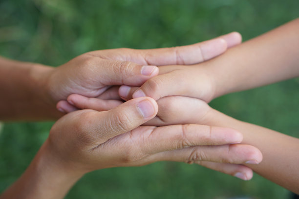 母亲和孩子手牵着手接受某样东西图片下载