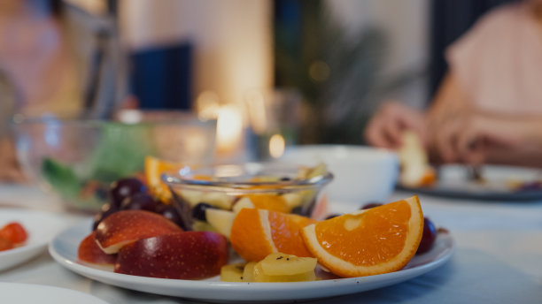 晚上，年轻的亚洲女性朋友坐在家里餐厅的餐桌上吃沙拉，聊天。生活方式健康饮食享受自然生活和植物性饮食。图片下载