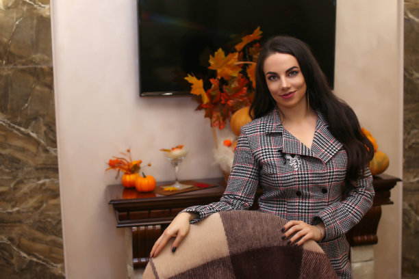 美丽优雅时尚的商务女性穿着一件连衣裙，值得在家里的室内壁炉在秋天图片下载