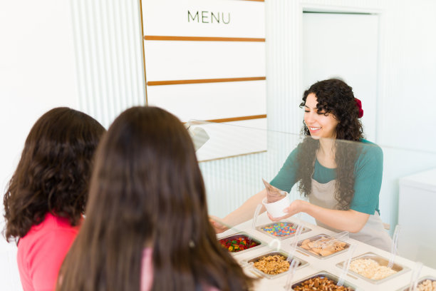 年轻的女士在卖冰激凌加配料或冻酸奶图片下载