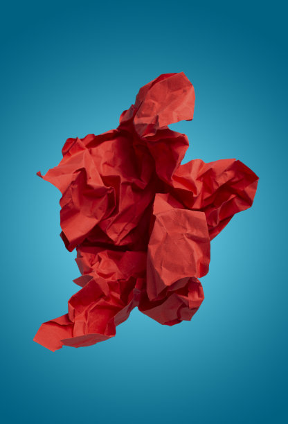 皱巴巴的红纸在蓝色背景上飞舞，创意抽象照片图片下载
