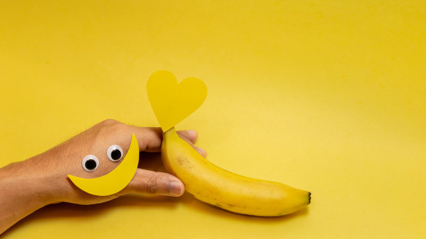 横幅上的手在前景中拿着微笑和黄色的心纸。空格为文字，黄色背景，概念一年中最快乐的一天，快乐的黄色天，夏天。图片下载