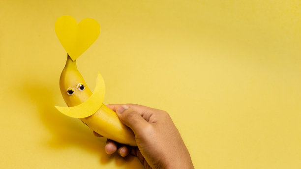 横幅上的手在前景中拿着微笑和黄色的心纸。空格为文字，黄色背景，概念一年中最快乐的一天，快乐的黄色天，夏天。图片下载