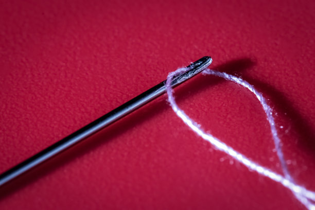 红色背景上的穿线缝纫针图片下载