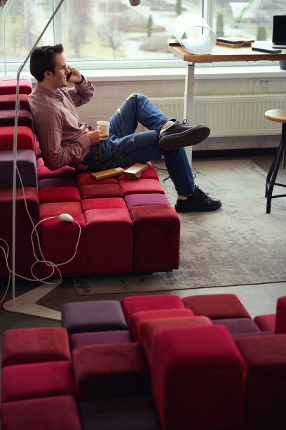 开心的年轻室内设计师在办公室用智能手机聊天图片下载