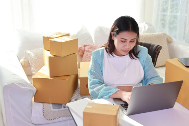 迷人快乐的亚洲孕妇坐在那里使用移动智能手机，用平板电脑为客户检查订单。准妈妈在怀孕期间为婴儿的出生做准备和工作。图片下载