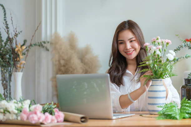 年轻的女花商在笔记本电脑上查看顾客的订单，在网上接受订单。图片下载