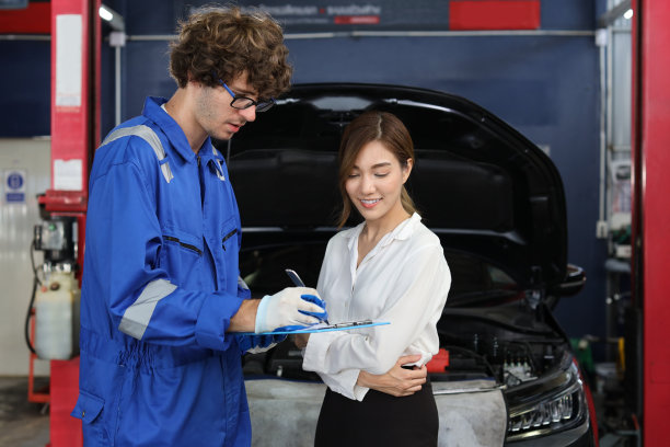 穿着制服的汽车机械师在维修站的剪贴板上展示汽车维修服务报告。汽车修理工给客户讨论她的汽车修理问题和状况图片下载