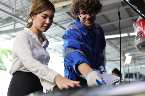 穿着制服的汽车机械师在维修站的剪贴板上展示汽车维修服务报告。汽车修理工给客户讨论她的汽车修理问题和状况图片下载