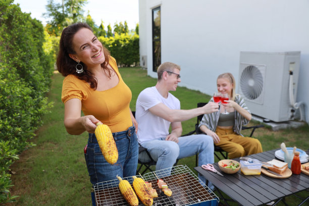 夏日里，一群快乐的家人或不同年龄的朋友在户外烧烤，喝着红酒，烤着玉米，在家里的后院花园享受烧烤派对图片下载