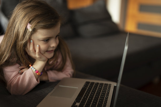 漂亮的女孩在笔记本电脑上看动画片。图片下载