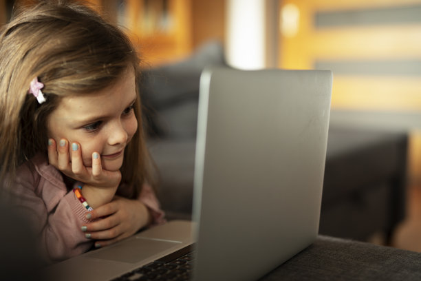 漂亮的女孩在笔记本电脑上看动画片。图片下载