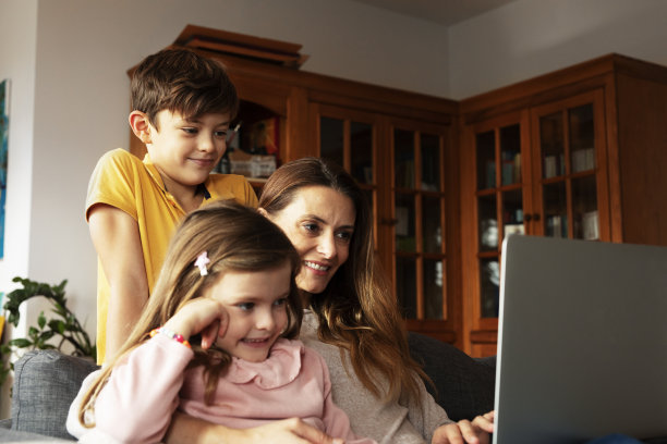 漂亮的女孩和妈妈一起看动画片。图片下载