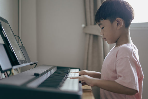 亚洲男孩坐在家里玩键盘图片下载