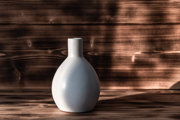 木制背景上的白色陶瓷花瓶。图片下载