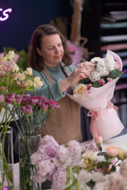 一个熟练的女花匠熟练地制作一个独特的花束从各种美丽的花图片下载