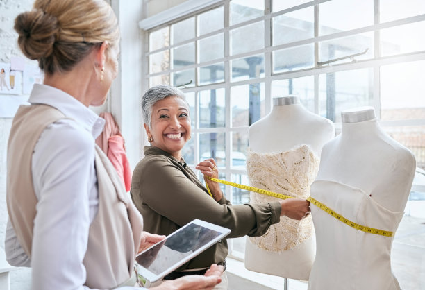 时尚，设计师和磁带与商务人士和人体模型的规划，电子商务和制造。管理，平板电脑和创意与女性在工厂工作室零售和网上购物图片下载
