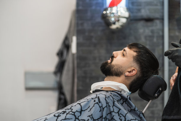 理发店的顾客斜倚在理发和修胡子的椅子上。图片下载