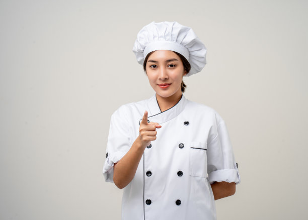微笑的年轻美丽的亚洲女厨师，穿着制服，在孤立的背景下摆姿势。女厨师职业厨师或面包师在厨房餐厅和酒店工作。图片下载