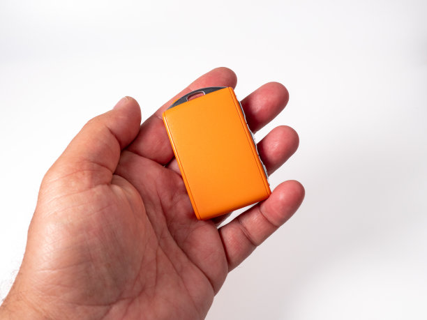 现代无线橙色点火钥匙在一个白色的背景在手。图片下载
