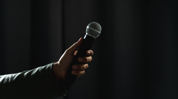 在公司商业活动中，自信成功的演说家在舞台上讲话，聚光灯照亮了黑暗。在会议大厅演讲的公众演说家。喜剧演员。图片下载