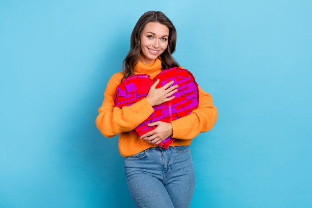 可爱的女友拥抱的照片，享受2月14日的礼物，从男朋友孤立的蓝色背景图片下载