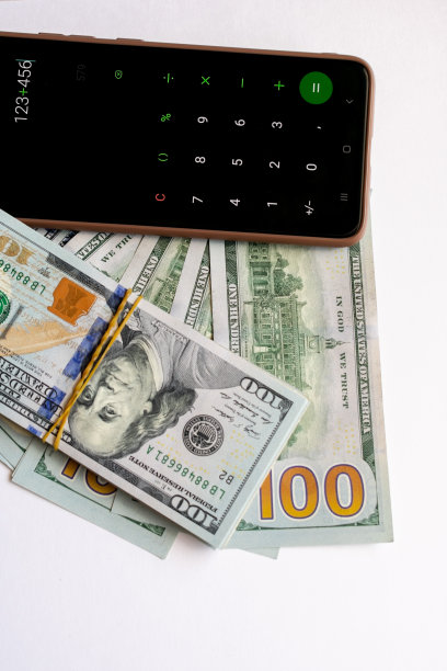 一叠一百美元的钞票和智能手机上的计算器。图片下载