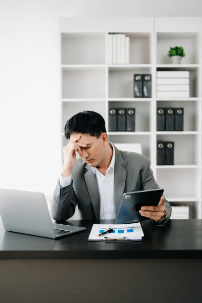 失意的年轻商人坐在办公室的办公地点用笔记本电脑工作图片下载