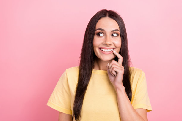 照片中狡猾时髦的女士穿着黄色t恤，手指，嘴唇，嘴巴看起来空白，孤立的粉红色背景图片下载