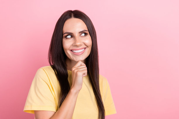 照片中若有所思的梦幻女子穿着黄色t恤，手臂下巴看起来空荡荡，孤立的粉红色背景图片下载