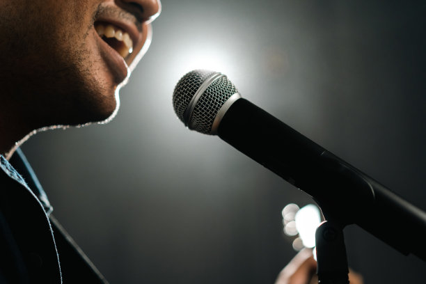 有魅力的歌手男子在舞台上唱着音乐，弹着吉他，聚光灯穿过音乐会的黑暗。音乐家在大厅里用灯光和烟雾现场表演。图片下载