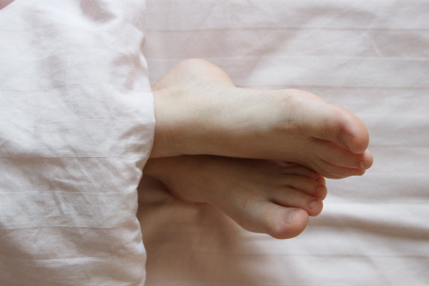 脚盖在床上的薄毯子下。健康的概念图片下载