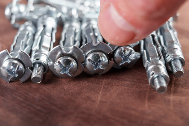 手拿莫利锚干墙紧固件。在黑板上图片下载