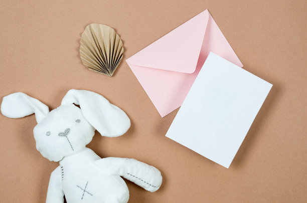 粉红色信封与空的白色卡片文字和白色毛绒兔子在米色背景图片下载