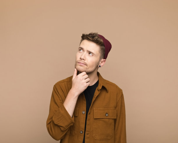 一个穿着棕色衬衫的忧心忡忡的年轻人抬起头来图片下载