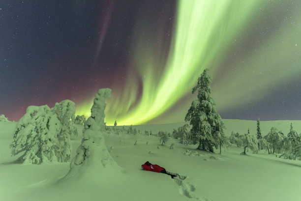 在北极光下躺在雪地里的徒步旅行者图片下载