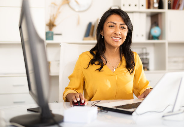 微笑的拉丁美洲女办公室职员在电脑上工作图片下载